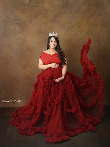 A royal portrait in red. Wearing a tiara and a magnificent ruffled gown, the mom-to-be exudes confidence and grace.