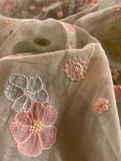 A close-up of our embroidered Mul Chanderi, showing the intricate floral threadwork on a sheer, pastel green base. It's a fabric that is pure poetry.
