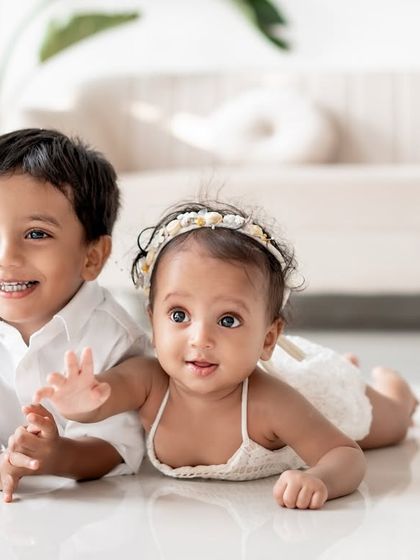 Two siblings lying on the floor together.