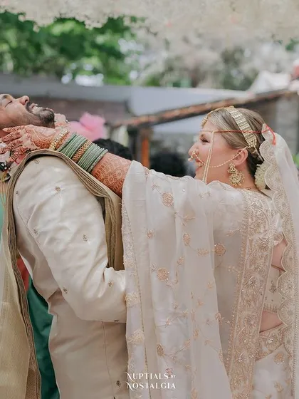 A playful moment during the wedding ceremony, with the bride lovingly grabbing the groom's face, capturing their fun-loving dynamic.