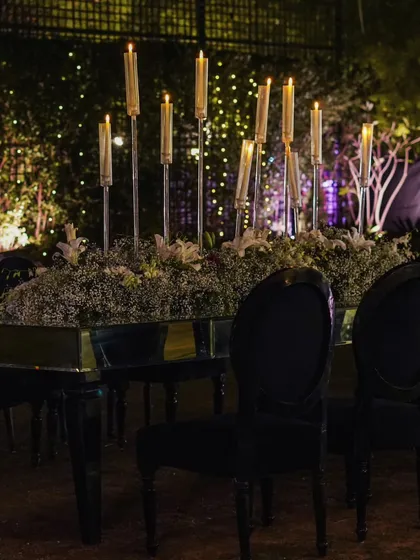 A long dining table with a mirrored top reflects the candlelight from the tall, modern candelabras, creating an endless path of light and romance.