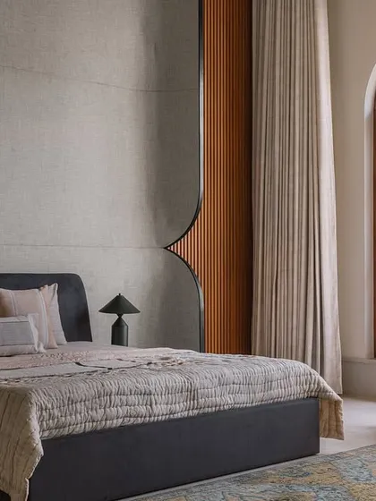 The parents' bedroom at Rehethaan is a serene retreat. The design features a custom bed with a fluted wood back panel and a comfortable rocking chair, creating a space that is simple, thoughtful, and elegant.