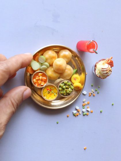 A mini Indian feast on a tiny plate, featuring pooris, aloo masala, and paneer butter masala.
