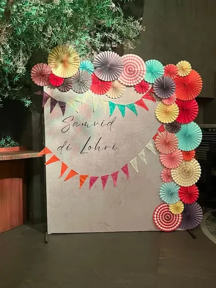 A closer look at the Lohri party photo booth, highlighting the vibrant paper fan decorations and bunting.