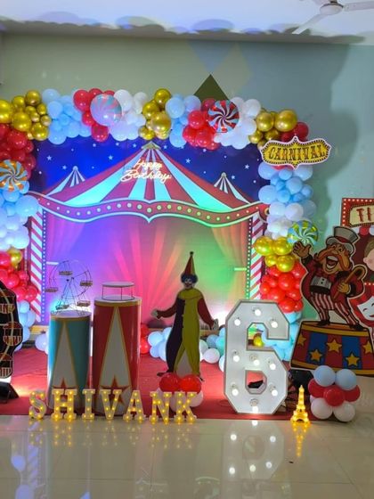 A vibrant carnival-themed 6th birthday party with a full stage, character cutouts, and a large marquee number.