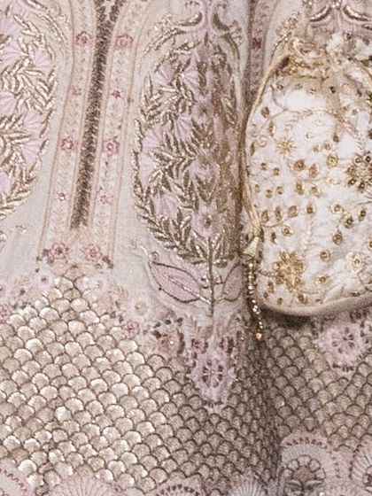 A detailed view of the lehenga's embroidery and the matching potli bag. The bag is included in the rental to complete your traditional look.