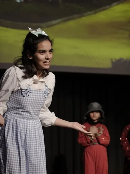 The character of Dorothy from 'The Wizard of Oz' addressing her friends. This image shows a lead actor confidently guiding a scene, demonstrating leadership and clear communication.
