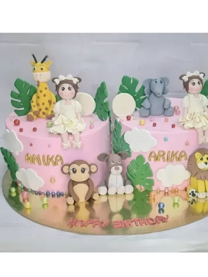 A jungle-themed cake for twin girls, Anika and Arika. This fresh pineapple cake is decorated with adorable handmade fondant animals like a giraffe, elephant, and lion.