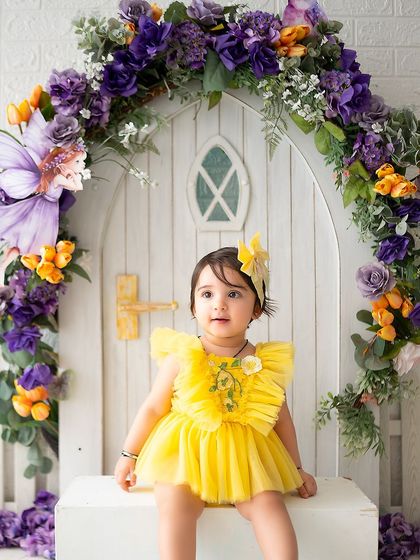 A sweet portrait of the birthday girl sitting in front of her magical fairy house.