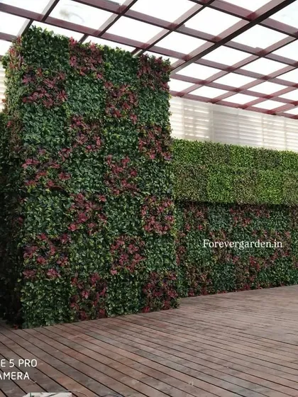 An expansive rooftop green wall installation, covering multiple surfaces to create a private, garden-like event space with a wooden deck.