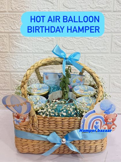 A full view of the hot air balloon hamper, featuring a jute cona basket filled with four types of snacks and a planter.