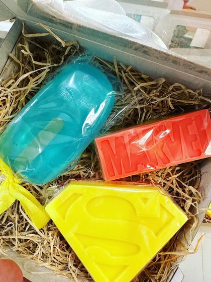 A custom superhero gift box with a mint popsicle soap, an orange Superman soap, and an orange Marvel soap.