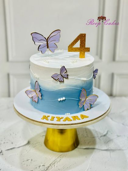 A serene butterfly-themed cake for Kiyara's 4th birthday. The blue and white ombre design is decorated with delicate purple butterflies, creating a calm and beautiful effect.