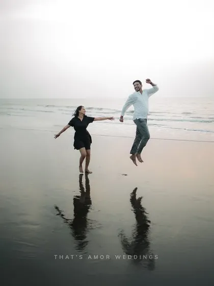 A fun, high-energy shot of a couple jumping for joy on the beach. Their reflections in the wet sand add a beautiful symmetry to this candid moment.