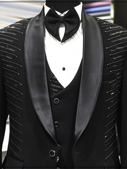 A black tuxedo with silver thread embroidery on the shoulders, displayed on a mannequin to show the full design.