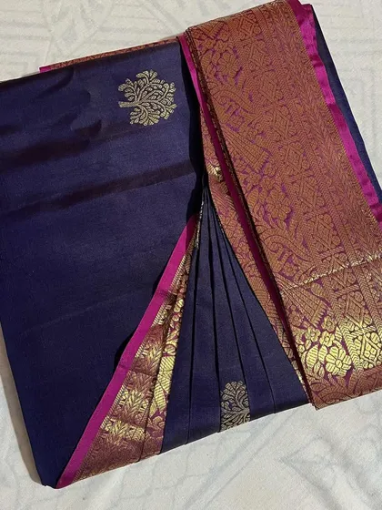A deep blue silk saree with a pink and gold border, showcasing a classic color combination.