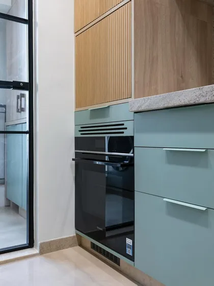Here, the fluted wood texture of the upper cabinets meets the smooth surface of the mint green drawers. This interplay of textures is a key element of the design, adding depth and interest to the overall aesthetic.