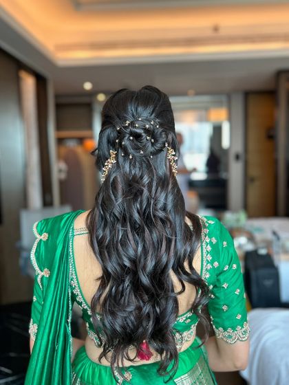 The back view of the popular half-bun style, showing the intricate knot and the beautiful cascade of curls.