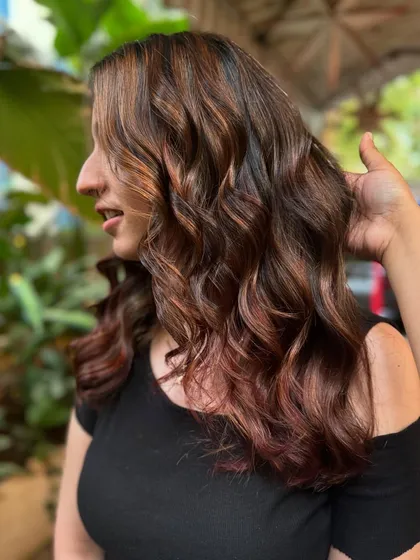 A side view of this brunette balayage with hints of magenta. It shows how you can add a playful touch to a classic look.