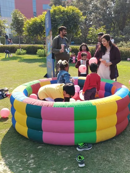 An inflatable round ball pool set up outdoors for a family day event. It provides a safe and fun activity for young children in an open-air setting.