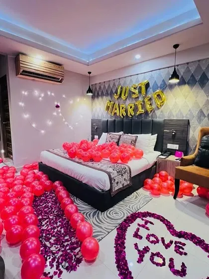 For a truly special "Just Married" or first-night surprise, I transform a hotel room into a romantic haven. This decoration features hundreds of balloons, a custom rose petal message on the floor, and elegant lighting.