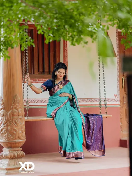 A serene solo portrait of the mother-to-be seated on a swing, framed by lush green leaves.