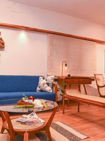 A glimpse into my studio space, showcasing a variety of teak furniture including a blue upholstered sofa, a daybed, and a rocking chair. This is where you can experience the warmth of my work.