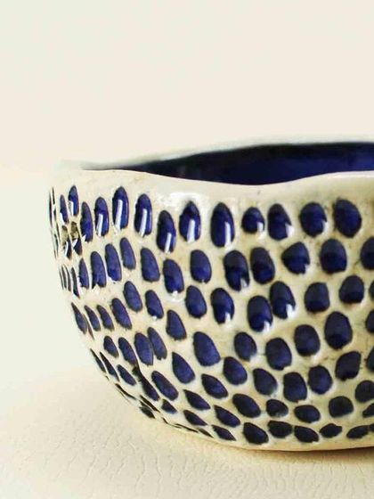 A detailed shot of the carved exterior of the Aqua Snack Bowl. The deep blue glaze fills each indentation, creating a pattern reminiscent of sea life or honeycombs.