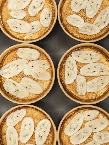 A tray of Banoffee Pies, fully assembled with banana slices and ready for the next layer of cream.