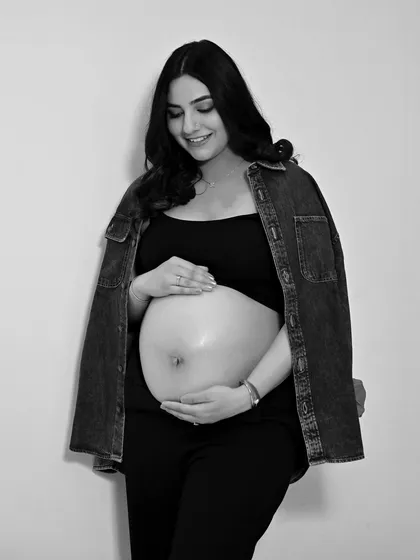 A simple, beautiful black and white portrait focusing on the baby bump. The casual denim jacket adds a modern, relaxed touch.