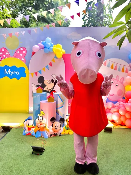 The Peppa Pig mascot makes an appearance at an outdoor party, posing in front of the colorful character backdrop. Mascot appearances are always a huge hit with the little ones.