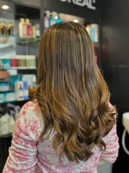 A perfect example of our highlighting work. We added golden and caramel tones to a dark base, creating a multi-dimensional look that is rich and full of warmth. The soft waves beautifully showcase the color blend.