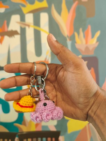 A close-up of handmade Amigurumi keychains, including a pink octopus and a yellow hat. These small, charming projects are perfect for beginners.