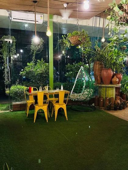 A cozy corner in our nursery cafe, perfect for a quiet chat. Surrounded by plants and the warm glow of hanging lights, this spot with its comfy swing chair is ideal for relaxing.