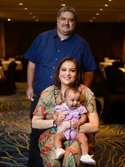 A happy family of three posing at an event. The baby's smile makes this a truly special and memorable family portrait.