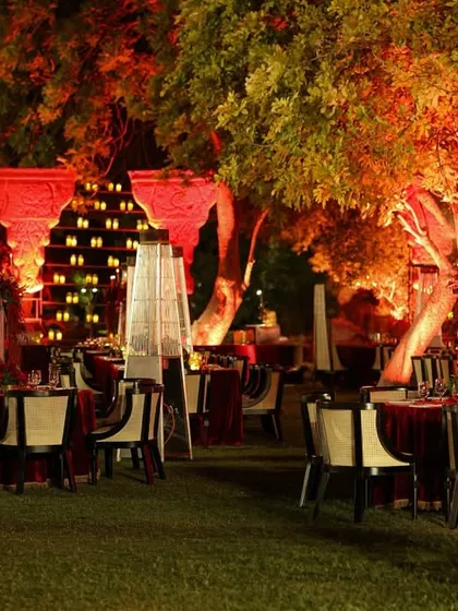 An overview of the moonlit garden dining setup, where each table glowed with candlelight, set against the backdrop of illuminated trees and a grand candle wall.