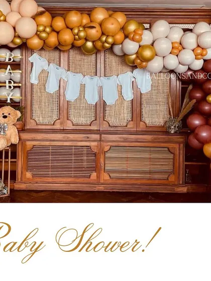 A rustic and charming baby shower setup. I used a garland of baby onesies and a beautiful balloon arch in warm, earthy tones to decorate the space.
