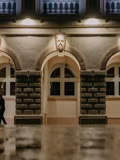 A couple embraces under the arches of a classic building, their figures reflected in the wet ground after a monsoon shower. This shot uses architectural framing and reflections to create a moody, artistic pre-wedding portrait.