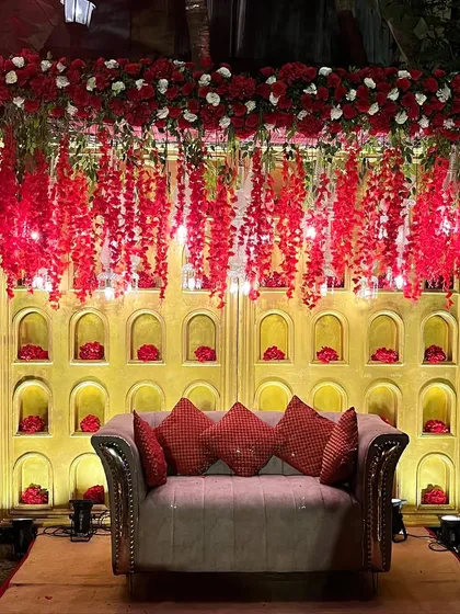 A cozy and elegant photo booth corner. The backdrop with floral niches and a comfortable sofa provides a perfect spot for guests to take pictures.