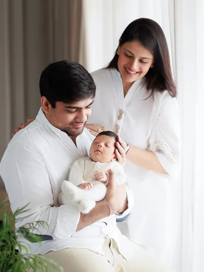 A beautiful family moment captured during a home session. The natural light from the window creates a soft and gentle atmosphere as they admire their newborn.