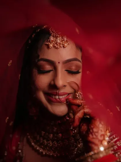 The quintessential blushing bride. This look focuses on a flawless, glowing base, soft smokey eyes, and a classic red lip, all framed by a delicate red veil for a timeless wedding day portrait.