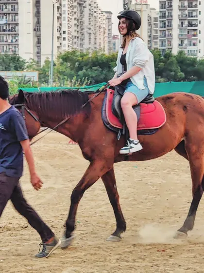 Your safety and confidence are our top priorities. This image shows a beginner rider on her first lesson, with one of our experienced trainers leading the horse to ensure a comfortable and secure introduction to riding.