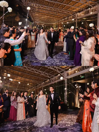 The couple makes a grand entrance at their reception, walking through an aisle of guests holding sparkler wands. This creates a magical, fairy-light tunnel effect.
