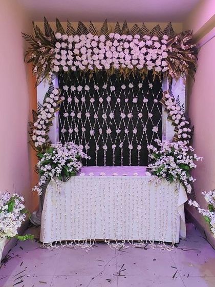 An elegant white floral setup with a dark backdrop featuring a diamond pattern of hanging flowers. This high-contrast design is both modern and sophisticated.