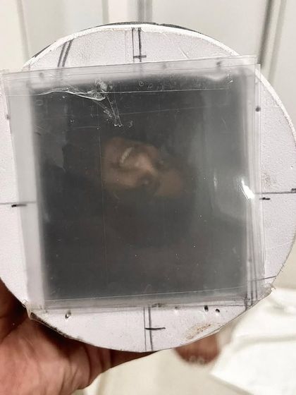 The "viewfinder" of a handmade camera, showing a reflection of the photographer. Building your own camera provides a deep, hands-on understanding of how images are captured.