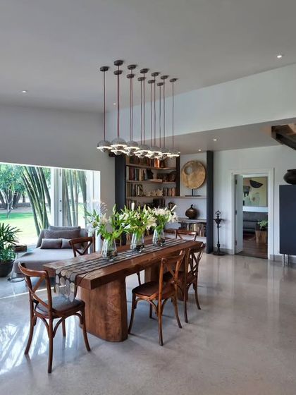 In the Aishbagh dining space, a table made from a single slab of teak from Borneo grounds the room with its strong presence. Above it, a cluster of modern pendant lights adds a contemporary touch, illustrating our love for mixing raw materials with refined design.