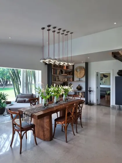 The dining space at Aishbagh, anchored by a solid teak slab table from Borneo. The room showcases our love for meaningful materials, including a silver-gilded Art Deco bar cabinet and a raw lava rock sculpture.