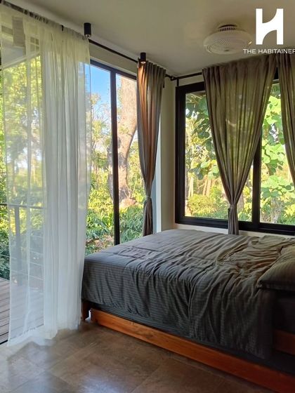 The bedroom in this Coorg cabin is surrounded by floor-to-ceiling windows, immersing guests in the natural landscape. This is the kind of unique experience that earns great reviews.