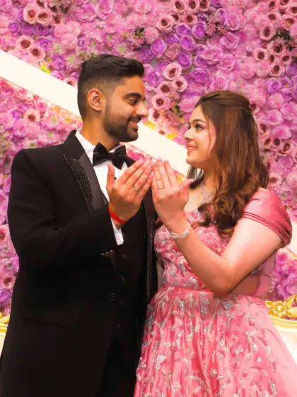 A sweet moment between the engaged couple against a wall of flowers. The bride's makeup is minimal and fresh, perfect for the romantic setting.