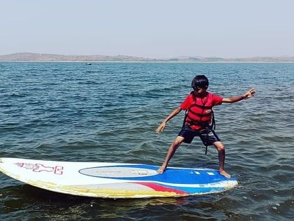 A young adventurer masters the art of stand-up paddleboarding on the vast Vani Vilas Sagara.
